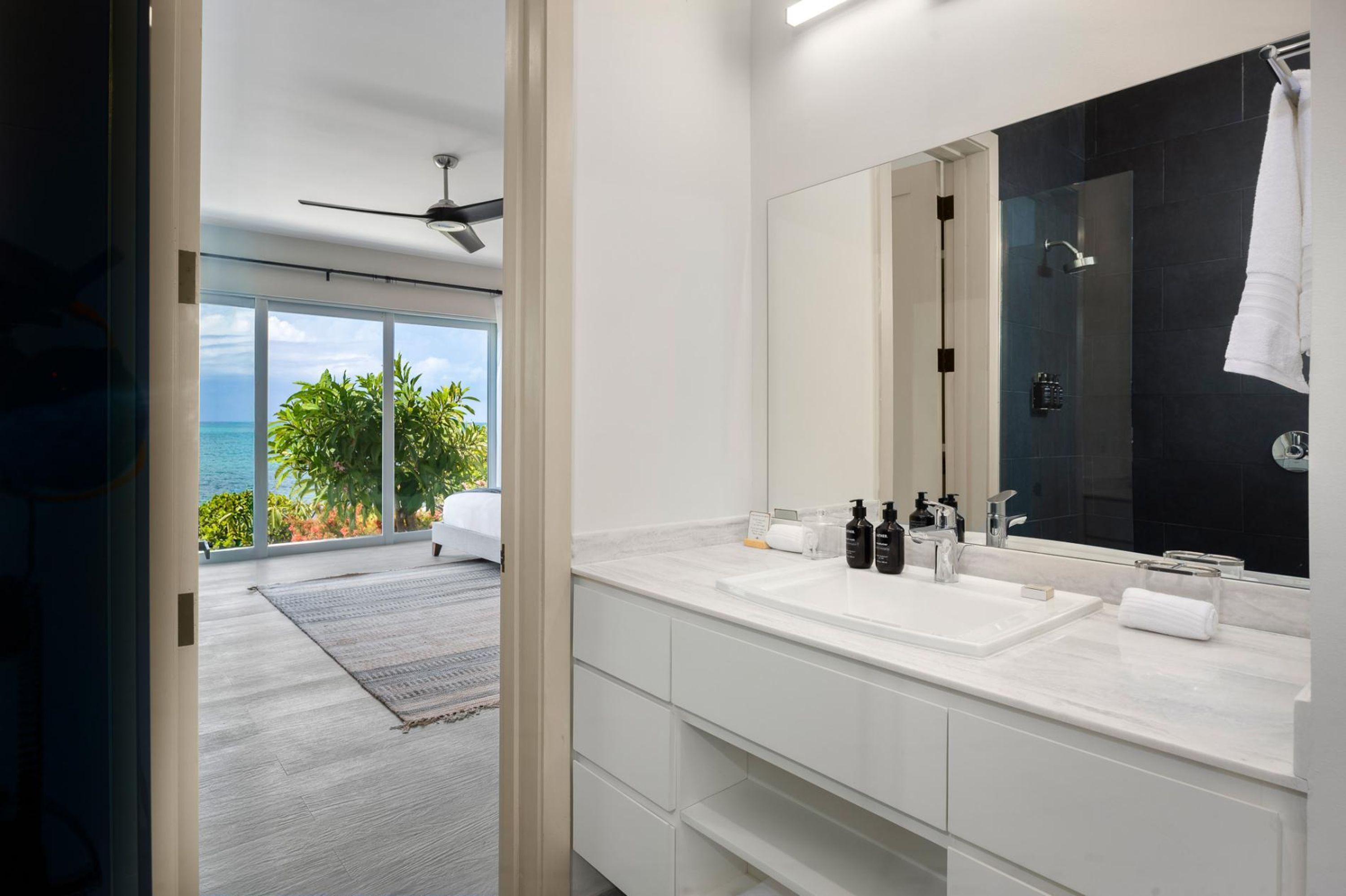 A modern bathroom with a large mirror, two sinks, and a shower.