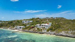 A coastal property with multiple modern houses on a hillside, overlooking a clear blue sea. - Villa Eden in Providenciales (Providenciales)