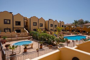 A hotel courtyard with two swimming pools, surrounded by potted plants and palm trees. - Apartamento Vanessa in Costa Adeje (Adeje)