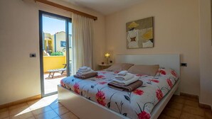 A bedroom with a bed, a nightstand, a lamp, and a view of an outdoor area. - Apartamento Vanessa in Costa Adeje (Adeje)