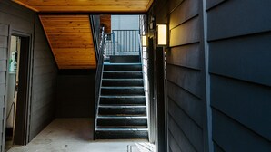 A narrow, enclosed stairway leading to a wooden upper level with a sloped ceiling.