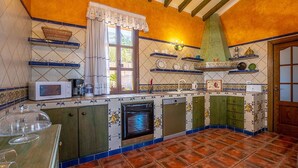 Une cuisine avec un mur recouvert de carreaux, un four à micro-ondes, une cuisinière et une fenêtre avec un rideau.
