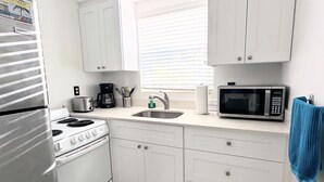 A compact kitchen with white cabinets, a stove, a microwave, and a sink. - Southwinds 9 for 3 King Studio Steps to Beach (Hollywood)