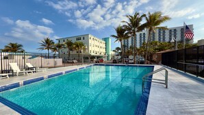 A swimming pool with a tiled edge, surrounded by lounge chairs and palm trees. - Beach Lover s Studio Apartment in Hollywood FL (Hollywood)