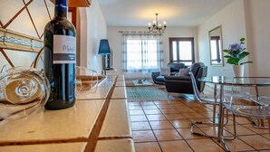 A modern living room with a dining area, a wine bottle, and a glass on the counter. - Apartamento Lava in Adeje (Adeje)