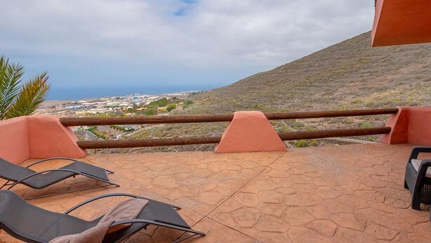 A terrace with lounge chairs, a view of the sea, and a hillside in the background. - Apartamento Lava in Adeje (Adeje)