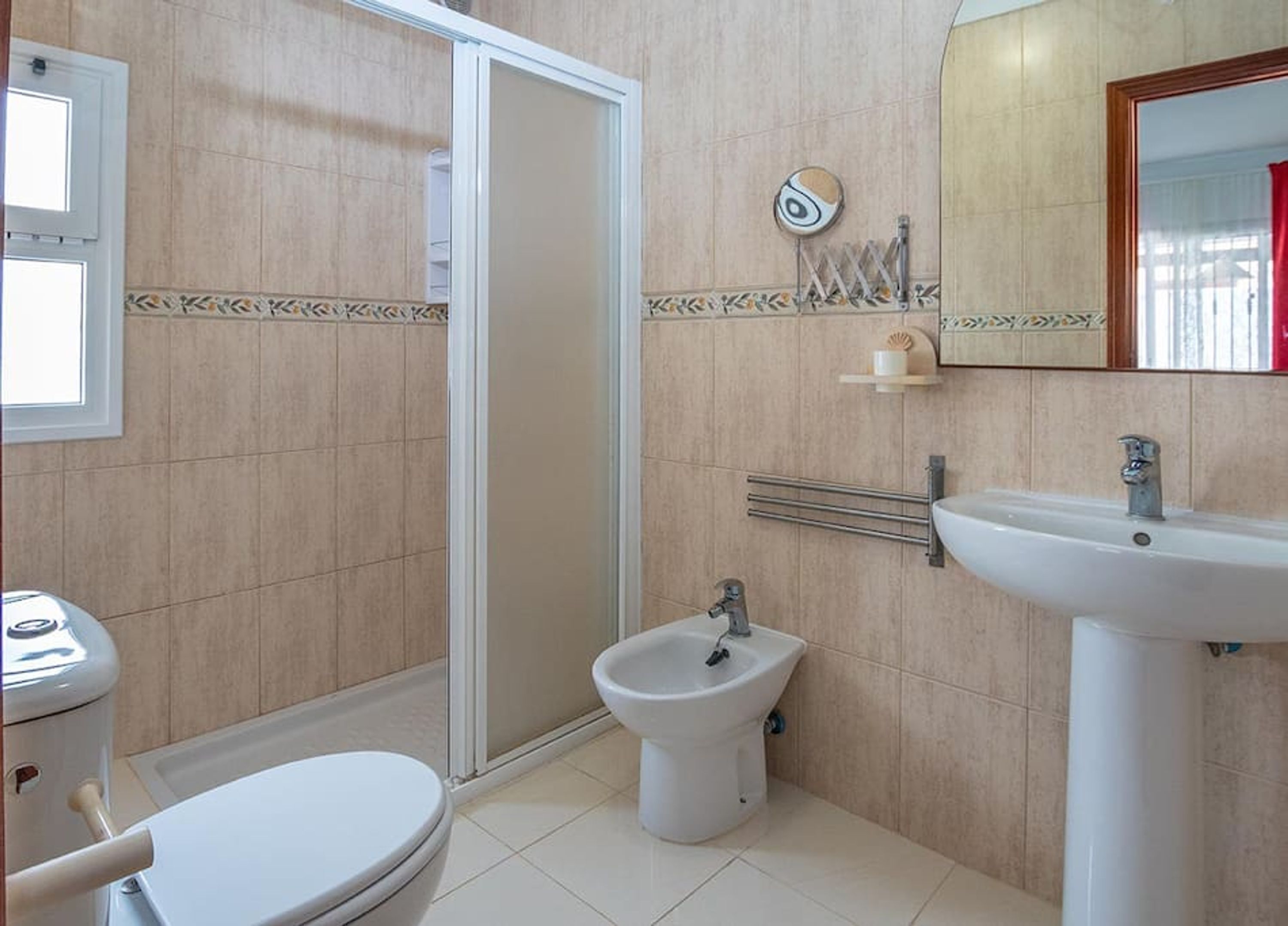 Un baño con inodoro, bidé, lavamanos y zona de ducha.