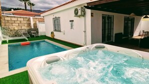 A swimming pool with a hot tub, outdoor seating, and a stone wall. - Villa Rosa in Callao Salvaje (Adeje)