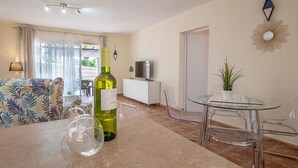 Ένα σαλόνι με έναν καναπέ, ένα τραπέζι από γυαλί και ένα μπουκάλι κρασί.