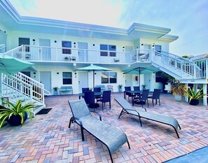 A hotel with a patio area featuring outdoor seating, a staircase, and a view of the building's multiple floors. - Southwinds 3 for 2 Queen Studio Steps to Beach (Hollywood)