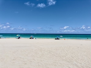 A beach with clear skies, calm waters, and a few umbrellas and lounge chairs. - Hollywood Boardwalk Studio Fully Equipped Kitchen (Hollywood)