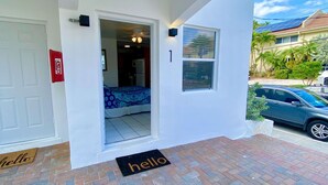 Une entrée d’immeuble d’habitation avec une porte, un détecteur d’incendie, un paillasson et une fenêtre.