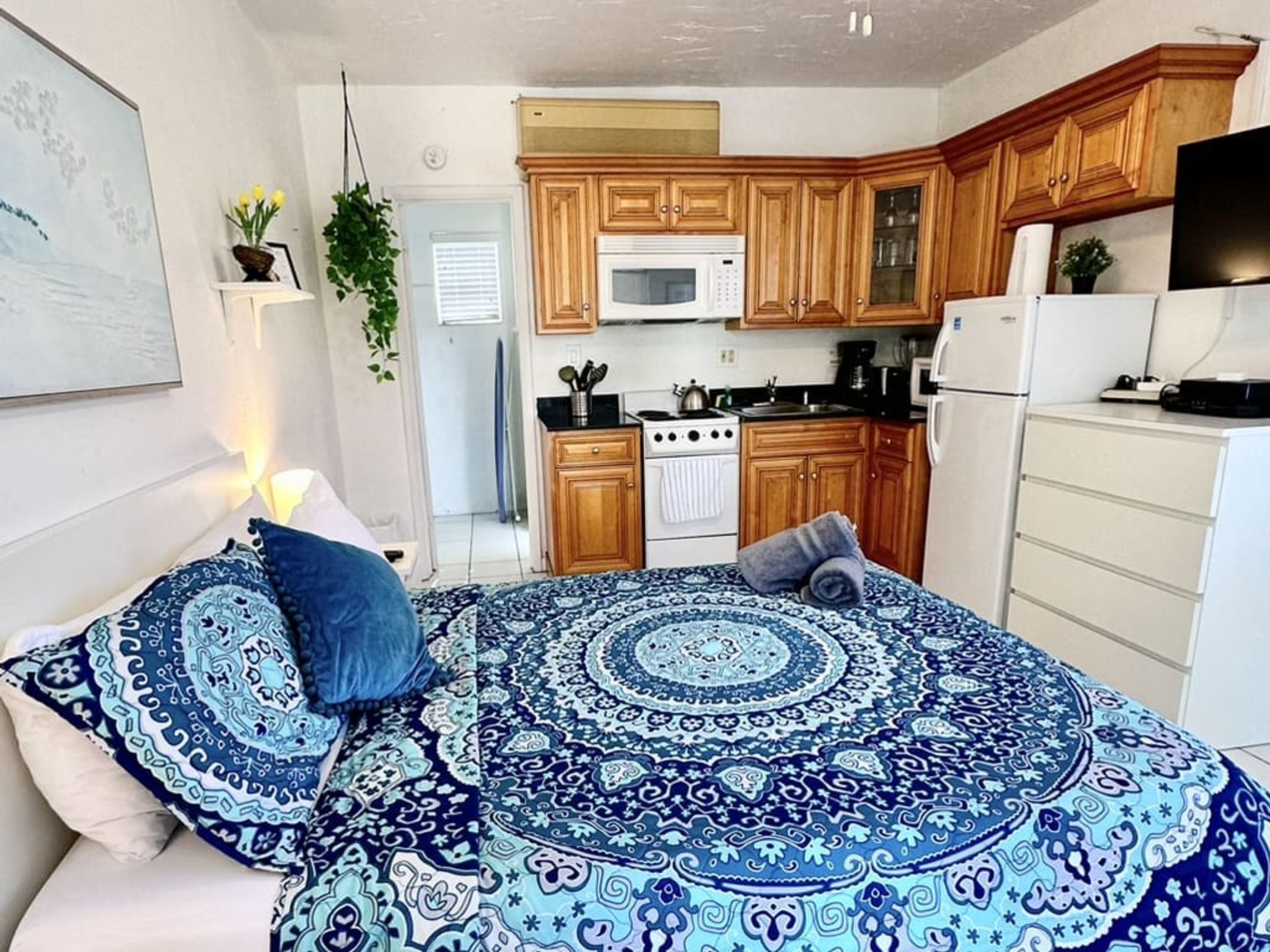 A bedroom with a patterned bedspread, a bedside table, and a nightstand.