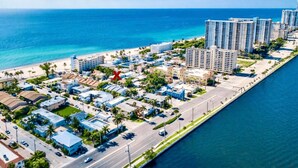 Vista aérea de una zona residencial costera con propiedades frente a la playa, un puerto deportivo y edificios de gran altura.