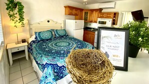 A bedroom with a patterned bedspread, a bedside lamp, a hanging plant, and a framed welcome sign. - Southwinds 8 for 2 Steps to Beach Boardwalk (Hollywood)