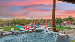 A hot tub area with a basketball court and playground in the background.