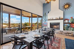 A dining area with a long table set for six, a fireplace, and a mural of cacti. - Sono - The Sonoran - Scottsdale - 16215 E Cavedale (Scottsdale)