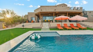 A modern house with a swimming pool, outdoor seating, and a covered patio area.