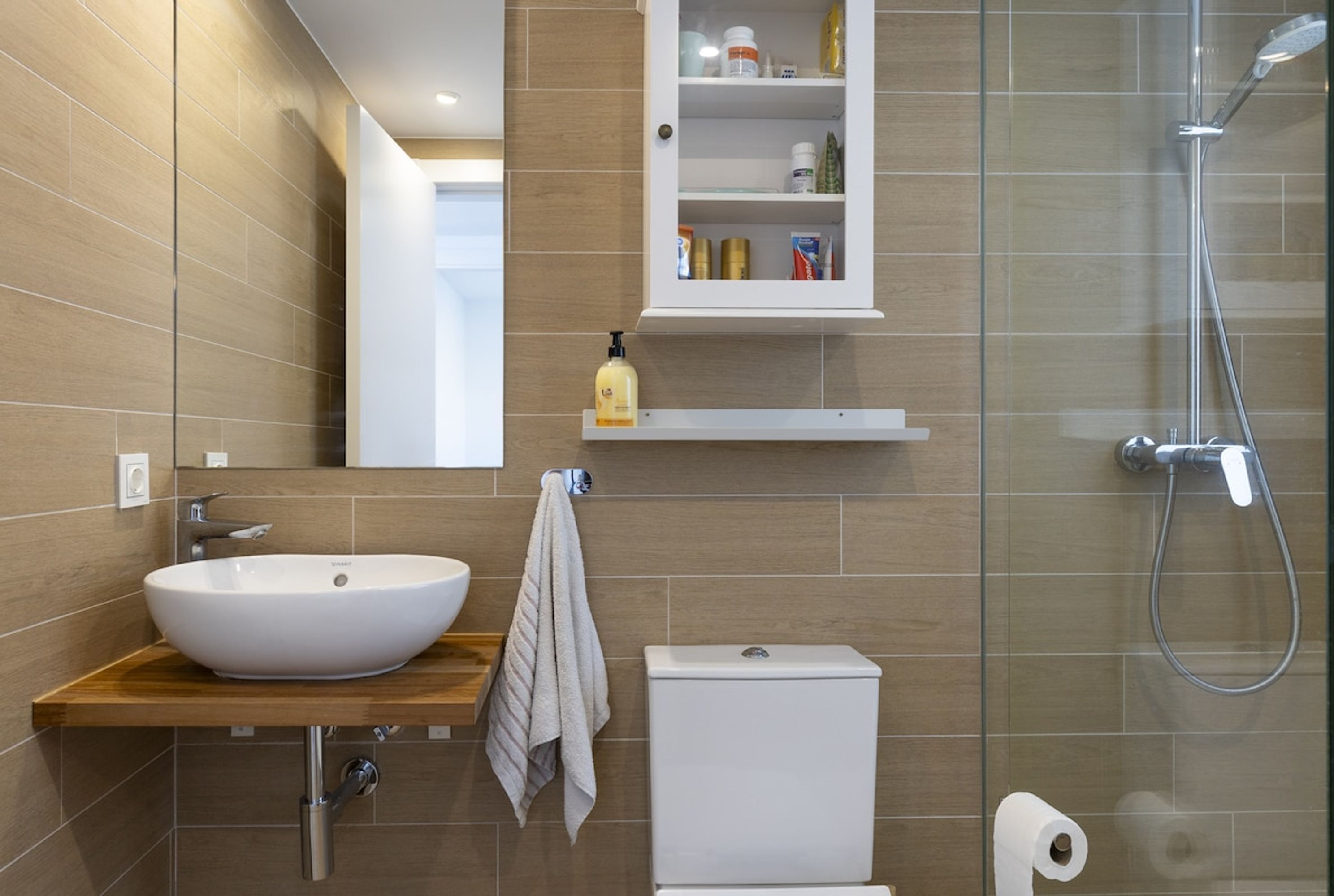 Une salle de bain moderne avec un grand lavabo blanc, des toilettes et une douche à parois de verre.