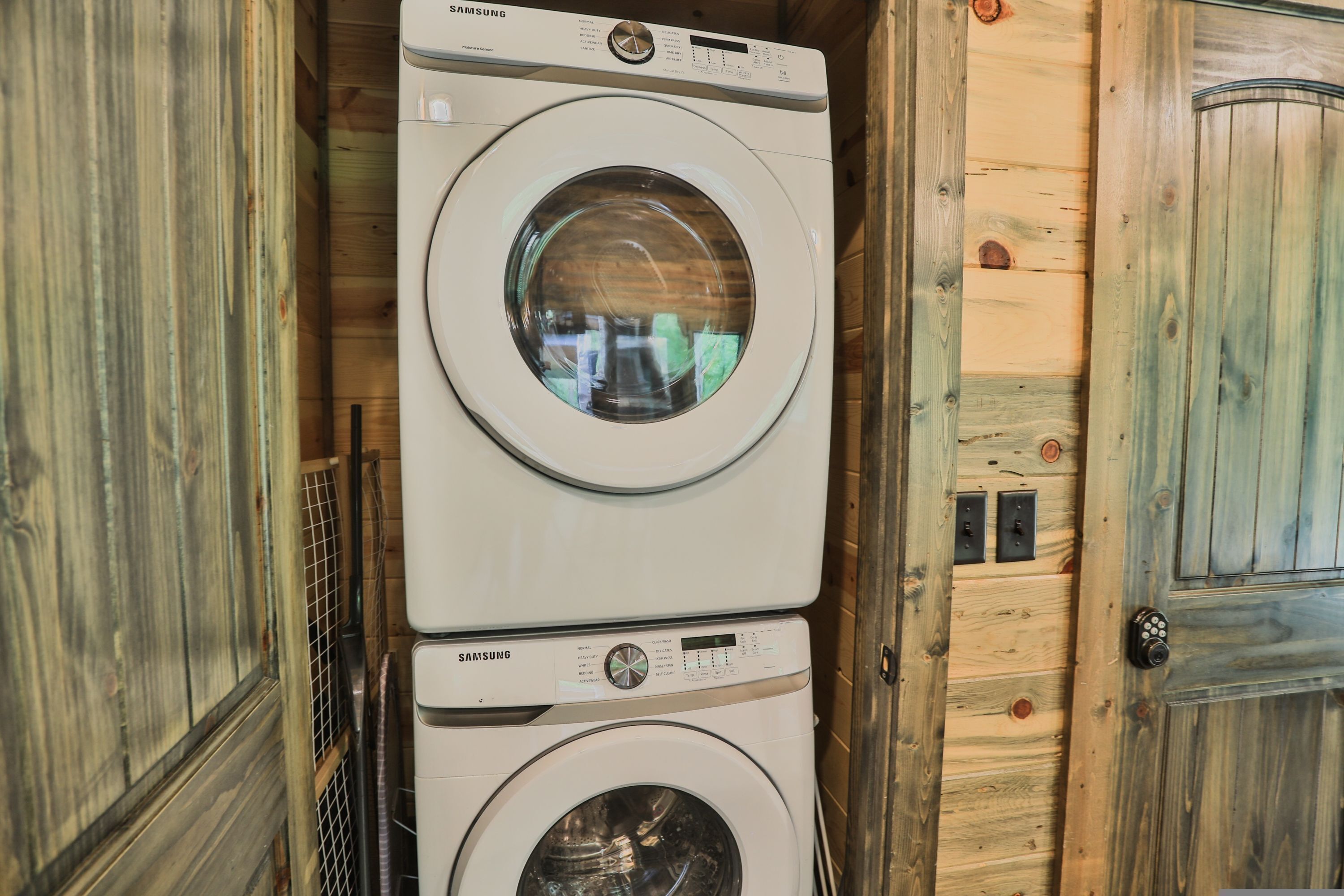 A stacked washer and dryer unit in a wooden cabin interior.