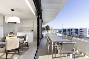 A modern balcony with a dining area, white cabinetry, and a view of the cityscape.