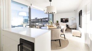 Een moderne woonkamer met een groot raam, een eethoek en een keuken.