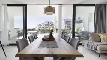 Een moderne eethoek met een houten tafel, grijze stoelen en een hangende lamp.