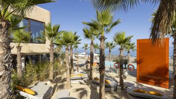 Een resort met palmbomen, ligbedden en een zwembad.