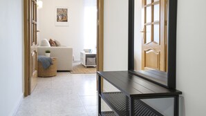A hallway with a wooden door, a white sofa, a small table, and a wicker basket. - Beachfront Apartment With Seaview Terrace (Fuengirola)
