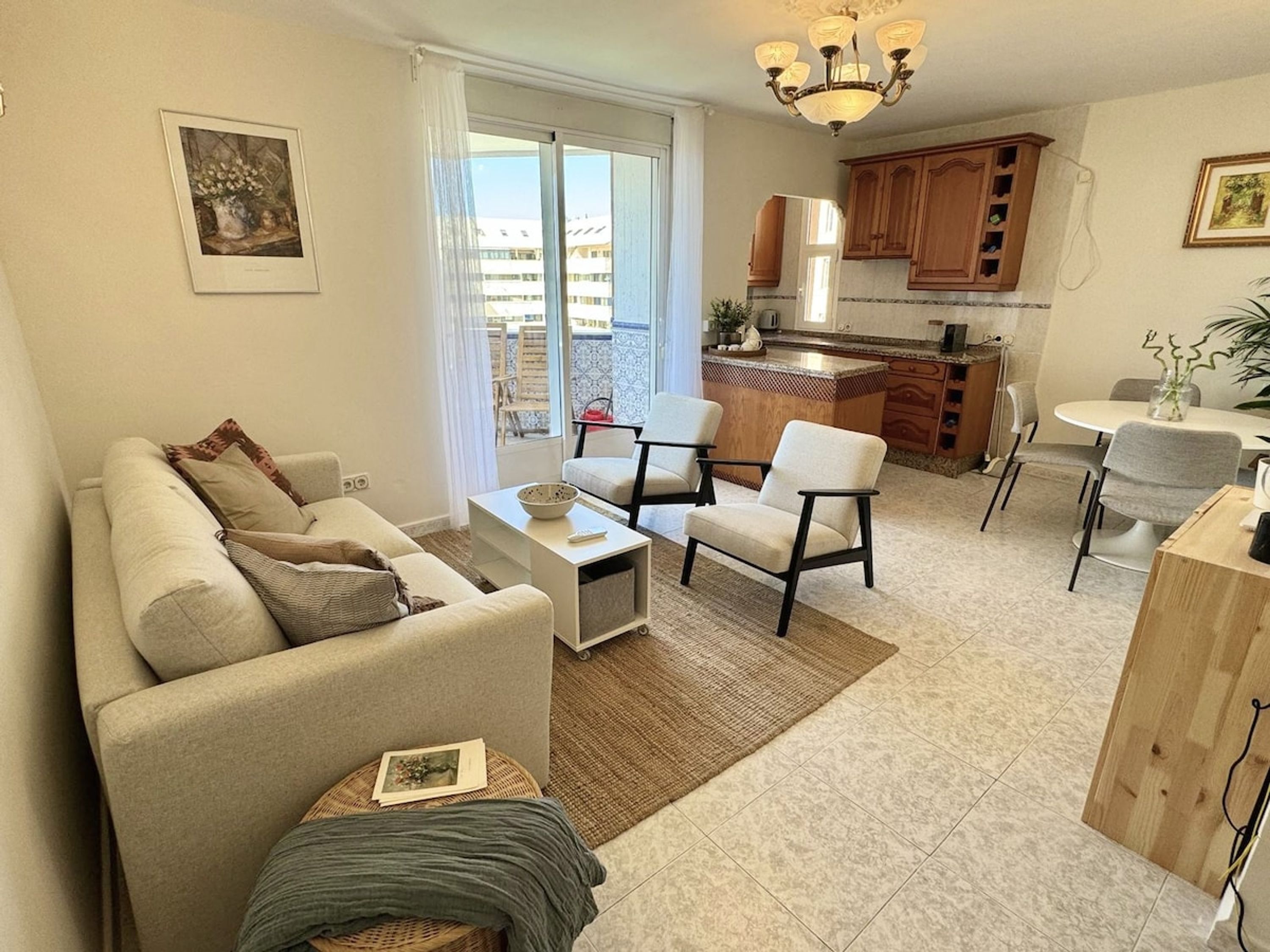 Uma sala de estar com sofá, poltronas, mesa de centro e um espaço de jantar com mesa e cadeiras.