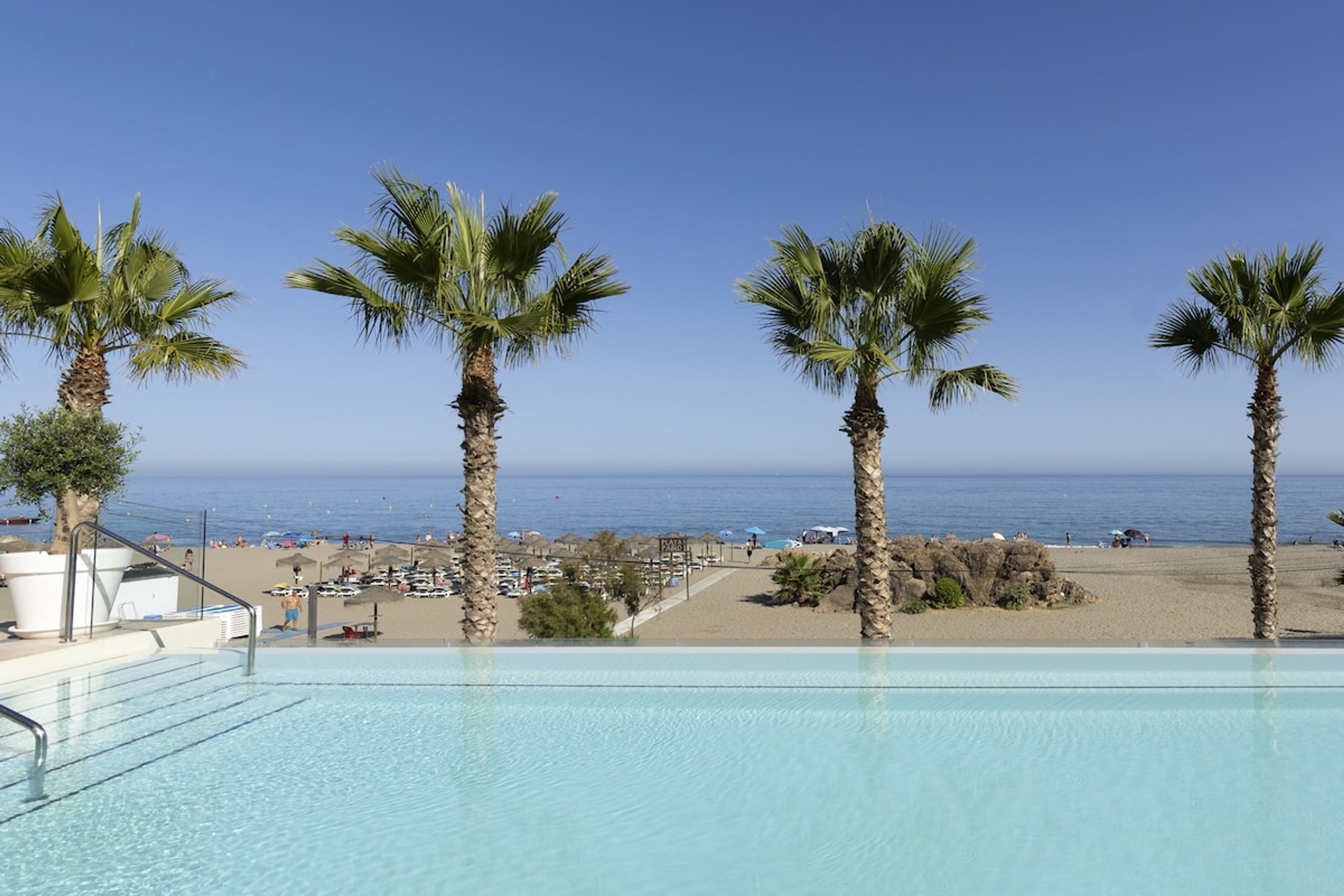 A poolside view with a clear view of the beach and ocean.