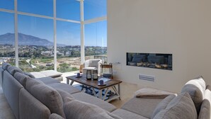 A spacious living room with a large window offering a city view, a comfortable sofa, and a small table with decorative items. - Casa Kodak - Las Lagunas de Mijas (Mijas)