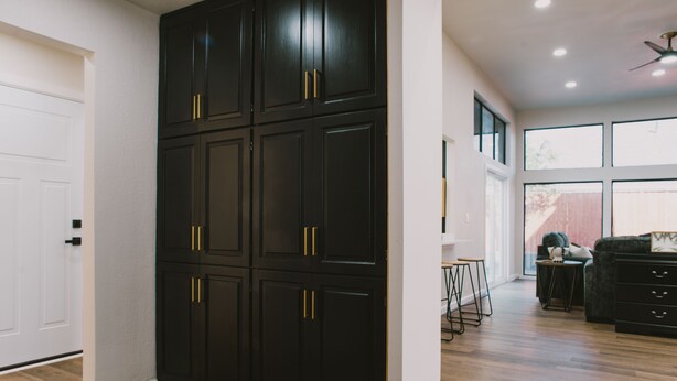 A spacious room with a large black wardrobe, a wooden floor, and a view of the outdoors through large windows. - Misha: 6443 Redpine Road, Dallas (Dallas)