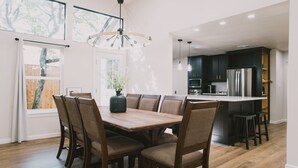 A modern kitchen with dark cabinets, stainless steel appliances, and a wooden dining table with chairs. - Misha: 6443 Redpine Road, Dallas (Dallas)