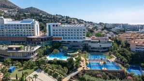 A hotel with multiple swimming pools, a central courtyard, and a mountainous backdrop. - Luxury Apartment With Terrace in Higueron (Fuengirola)