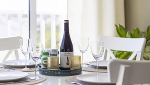 A dining table with a bottle of wine, glasses, and a decorative tray. - Central Apartment With Seaview Terrace and Pool (Benalmádena)