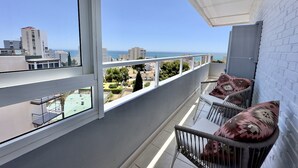 A balcony with a view of the sea, white walls, and a patterned cushion. - Central Apartment With Seaview Terrace and Pool (Benalmádena)