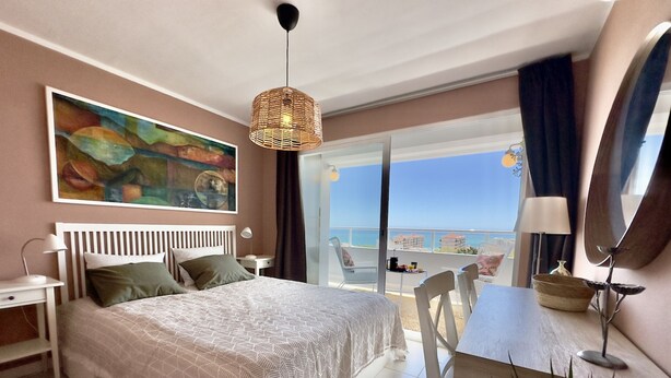 A bedroom with a large bed, a desk, and a view of the sea. - Central Apartment With Seaview Terrace and Pool (Benalmádena)
