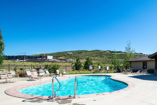 A swimming pool with lounge chairs and a view of a hilly landscape. - Nret - Park City - 13546 N Noah Court (Kamas)