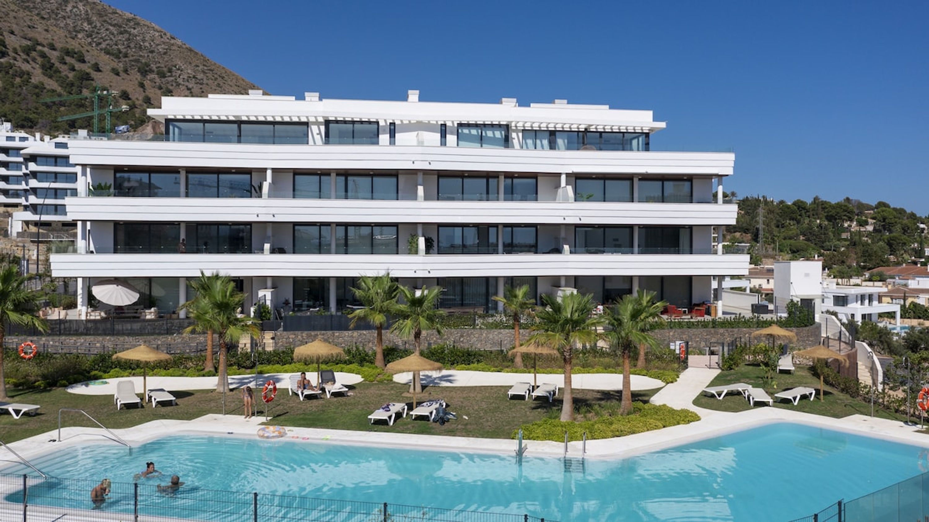 Un hotel moderno con zona de piscina, varios pisos y vistas al paisaje circundante.