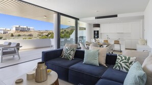 A modern living room with a sofa, a dining area, and a kitchen. - Exclusive 3-bedroom Apartment in Higueron (Fuengirola)