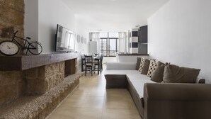 Een moderne woonkamer met een stenen openhaard, een eethoek en een bank met gestreepte kussens.
