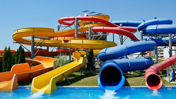 Een waterpark met meerdere glijbanen in geel, rood en blauw.