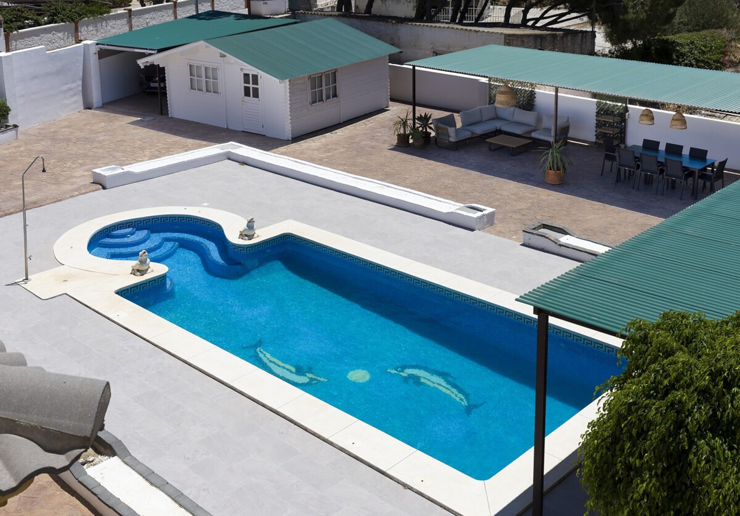 A swimming pool with a dolphin-shaped design, surrounded by outdoor seating and covered areas.