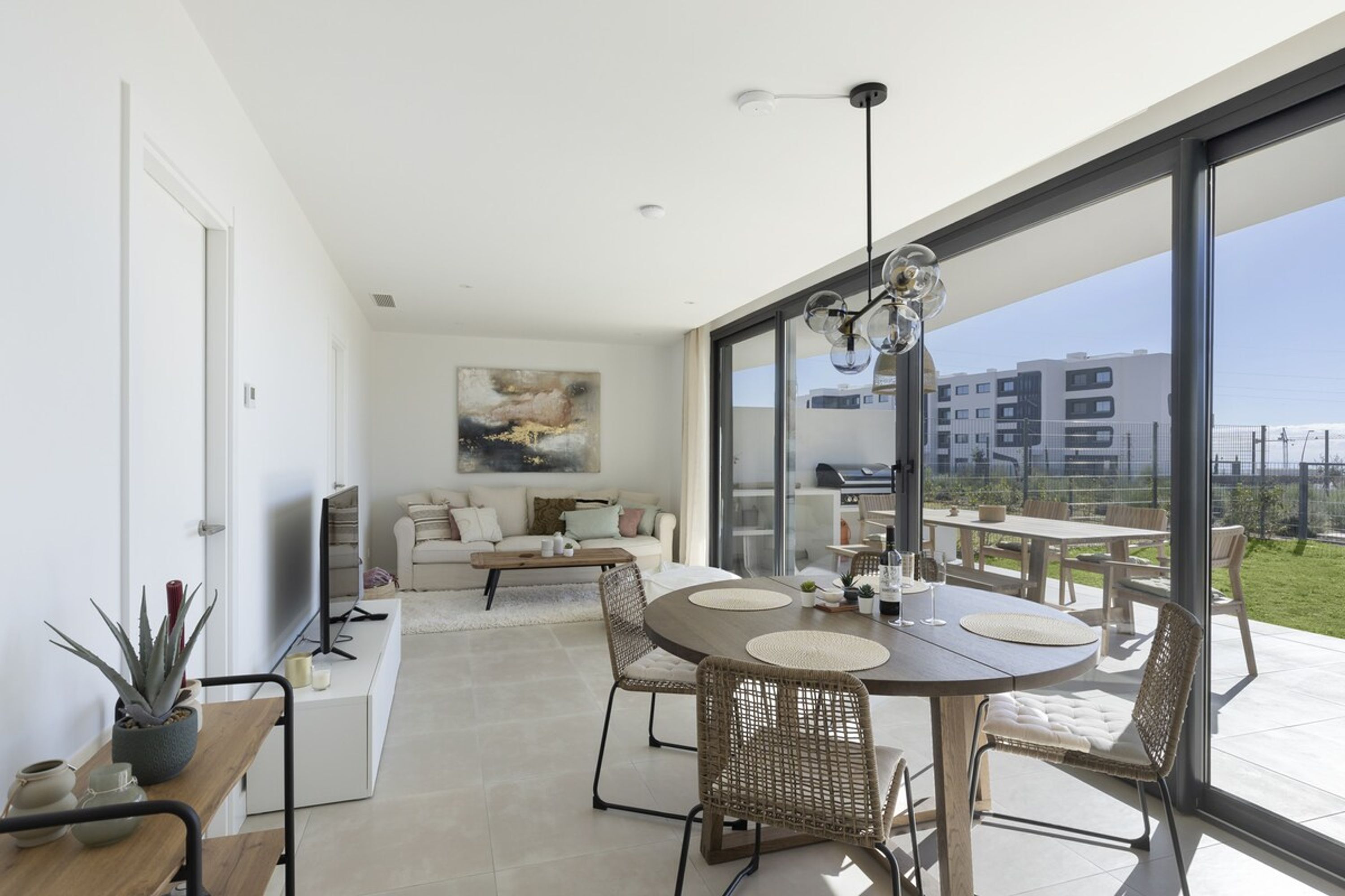 A modern living room with a dining area, large windows, and a view of the city.