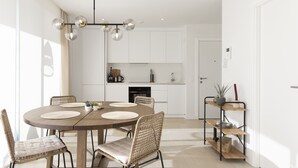 Una cocina moderna con armarios blancos, una mesa de comedor redonda con sillas tejidas y una lámpara colgante.