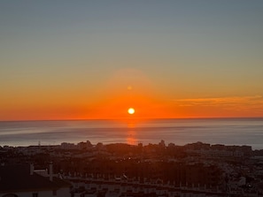 A sunset over a coastal cityscape with buildings in the foreground.