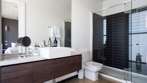 A modern bathroom with a large mirror, white sink, dark wood vanity, and a glass-enclosed shower area. - Aquabelle Three on Rye Beach (Melbourne)