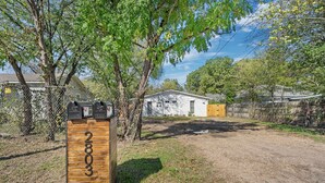 A wooden mailbox with the number 2803, a fenced yard, and a small white building with a yellow door. - Flint B (Waco)