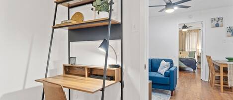 Un salon moderne avec un bureau en bois, un canapé bleu et un ventilateur de plafond.